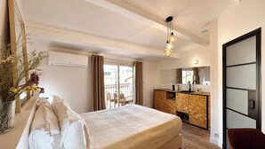 Quarto de hotel com cama, escrivaninha, cadeira, espelho e vista para o exterior.