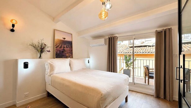 Quarto com cama, pintura, vaso de flores e varanda com vista.