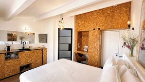 Quarto de hotel com cama, cozinha compacta, banheiro e vista para a cidade.