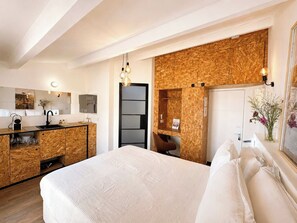 Une chambre d’hôtel avec un lit, une kitchenette, une salle de bain et une vue sur la ville.