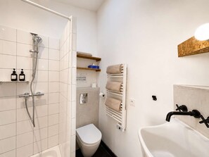Une salle de bain avec douche, toilettes et baignoire.