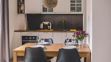 Una cocina moderna con armarios blancos, encimera de madera y una mesa de comedor para dos.