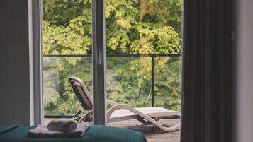 Una habitación con una cama, una ventana con vistas a zonas verdes y una silla afuera.