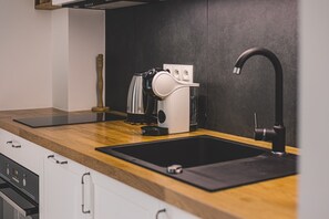 A modern kitchen with a black sink, a coffee machine, and a wooden countertop.