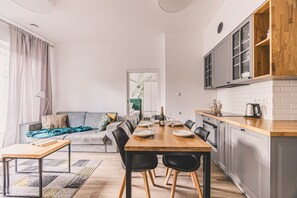 Eine moderne Küche mit Essbereich, grauem Sofa und Blick ins Freie.