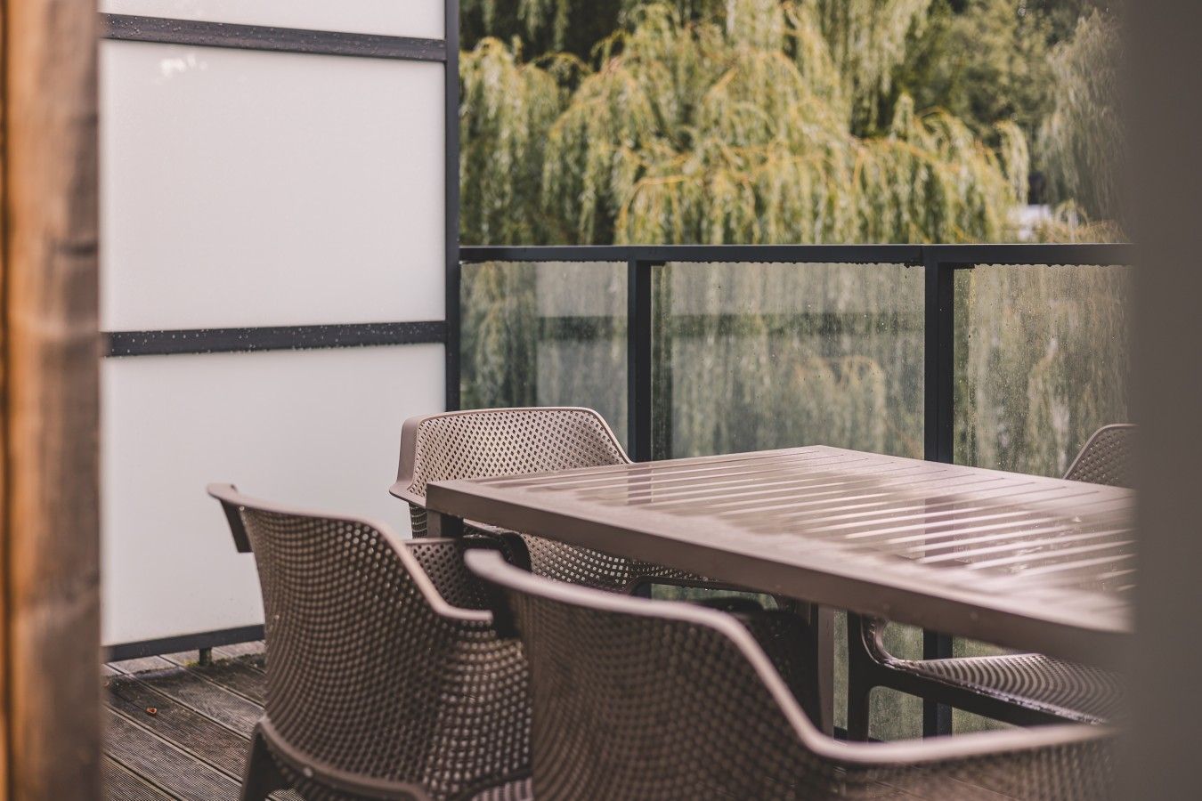 Ein Balkon mit Tisch und Stühlen mit Blick auf einen Garten mit Bäumen.