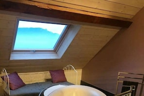 A room with a sloped ceiling, a skylight, a bed with a metal frame, and a window. - Holiday home in Trevigin with Wi-Fi (TREVIGNIN)