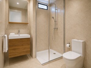 Une salle de bain moderne avec une douche à parois de verre, un meuble-lavabo en bois et des toilettes blanches.