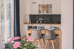 A modern kitchen with white cabinets, a wooden countertop, and a dining area with two chairs and a table set for two.