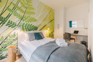 A modern bedroom with a bed, a desk, and a chair. - Castor Apartament  | Z Tarasem przy Puszczy (Hajnówka)