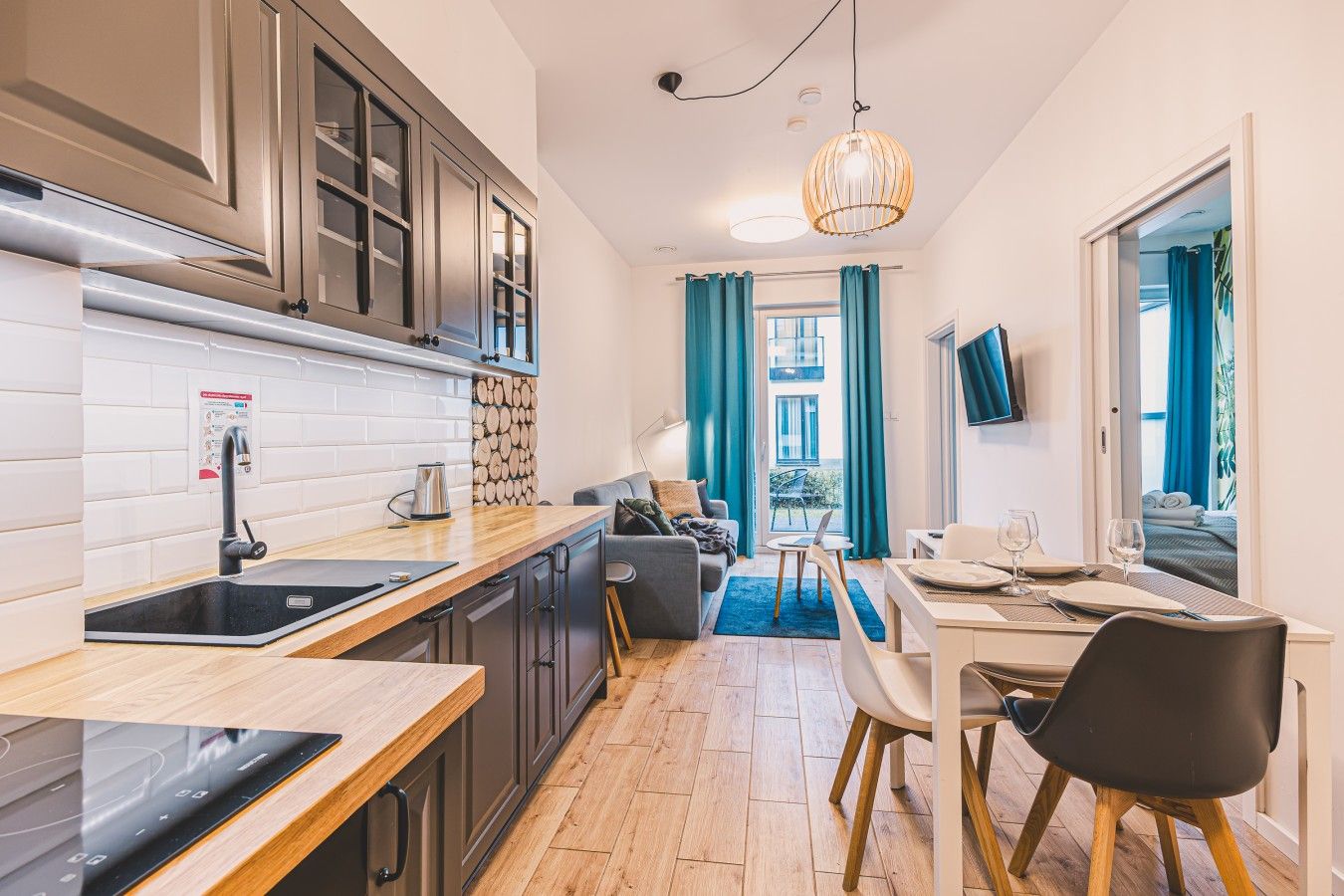 Habitación de hotel compacta con kitchenette, comedor y sala de estar con vistas al exterior.