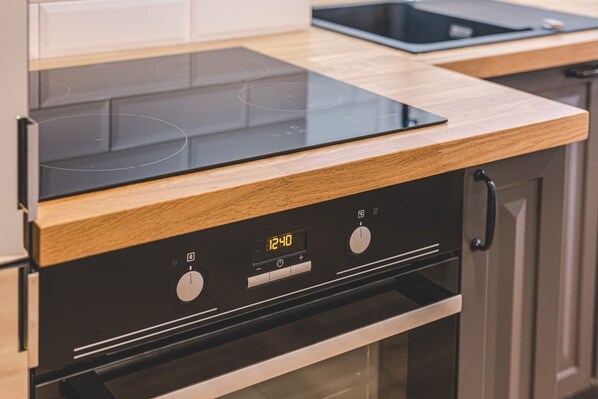 A modern kitchen with a black induction cooktop and wooden cabinetry.