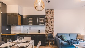 Une cuisine moderne avec des meubles de couleur sombre, un plan de travail en bois et un luminaire suspendu.