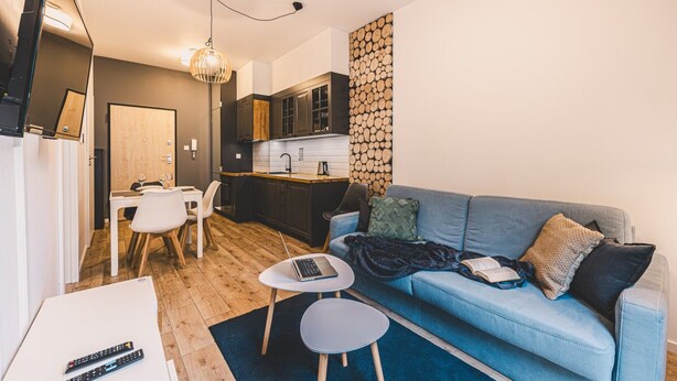 Un espace de vie compact comprenant un coin cuisine, un coin repas et un espace détente avec un canapé et une petite table basse.