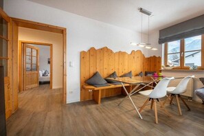 Une chambre avec une tête de lit en bois, une table à manger avec des chaises et une fenêtre donnant sur un beau paysage.