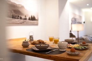 Et morgenbord med tepotte, skåle, glas med appelsinjuice og en tallerken med skiver af agurk.