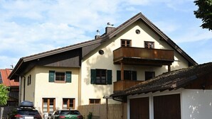 Een huis met twee verdiepingen, een balkon, een garage en een auto voor de deur.