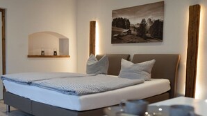 Een moderne slaapkamer met een groot bed, een nachtkastje, een spiegel en een schilderij aan de muur.
