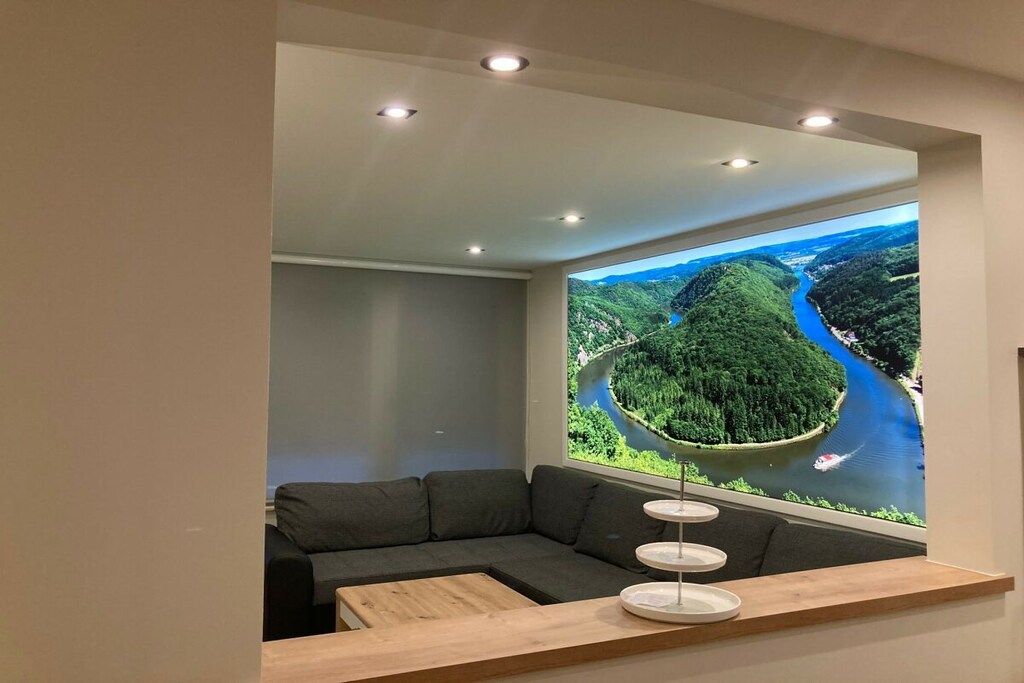 A modern living room with a large window, a gray sofa, and a wooden coffee table.