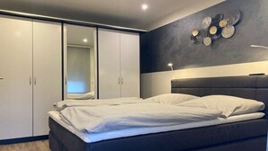 A bedroom with a bed, a wardrobe, and a wall-mounted light fixture. - Holiday apartment with 2 bedrooms (Merzig-Ballern)