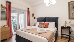 Ett hotellrum med en säng, ett sängbord, en lampa, en spegel och utsikt över omgivningarna.