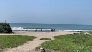 Ein Strand mit blauem Himmel, einem Weg zum Wasser und einem Schiff in der Ferne.