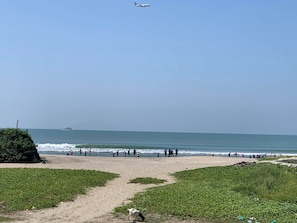 Una playa con cielo despejado, un camino que lleva al agua y un barco a lo lejos.