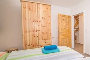A bedroom with a bed, a wooden wardrobe, and a staircase leading to another room. - Ilsestein - Detached house (Ilsenburg)