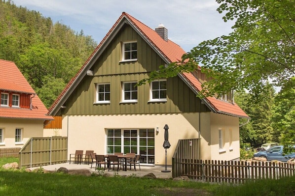 A two-story building with a sloped roof, a balcony with seating, and a fenced outdoor area. - Ilsestein - Detached house (Ilsenburg)