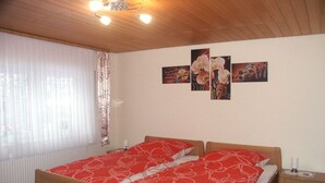 A bedroom with a double bed, a nightstand, a lamp, and artwork on the wall. - "To the dike warden" (Losheim am See)