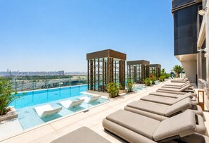 A rooftop pool area with lounge chairs and a view of the city skyline. - HAVN - Studio in Regalia, Business Bay (Dubai)