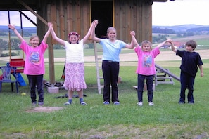 A group of people standing in front of a wooden structure with a grassy field in the background.