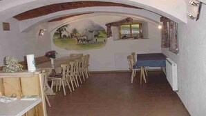 Espaço de refeições com um mural, mobiliário de madeira e vista através de um arco.