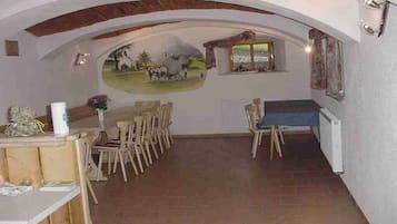 A dining area with a mural, wooden furniture, and a view through an archway.