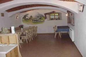 Zona pranzo con un affresco, arredi in legno e vista attraverso un arco.