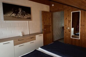 A bedroom with a bed, a wooden wardrobe, a mirror, and a door leading to another room. - Holiday home in Extertal-Rott with barbecue (Extertal-Rott)