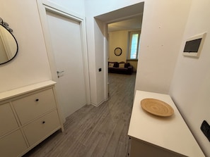 A hallway with a door, a small cabinet, and a round wooden object on a table.