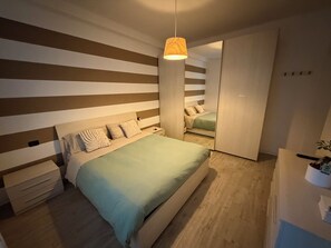 Une chambre à coucher comprenant un lit, des tables de chevet, un luminaire suspendu et une armoire.