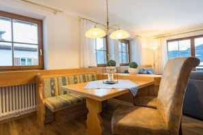 Uma área de refeições aconchegante com mesa de madeira, bancos e um lustre.