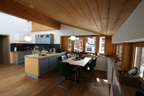 A modern kitchen with wooden cabinets, a central island, and a dining area with chairs. - Alpenflair holiday apartment 316 (Oberstdorf)