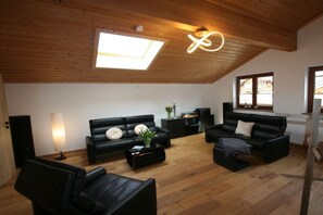 A modern living room with a wooden ceiling, black leather sofas, a coffee table, and a skylight. - Alpenflair holiday apartment 316 (Oberstdorf)
