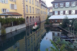 Um canal ladeado por edifícios, com uma estátua e um barco.