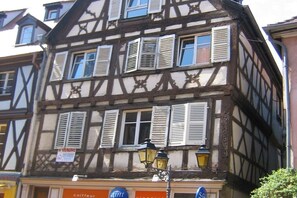 Ein traditionelles Fachwerkhäuschen mit mehreren Fenstern, von denen einige mit Fensterläden versehen sind, und einem Schild, das auf einen Ausverkauf hinweist.