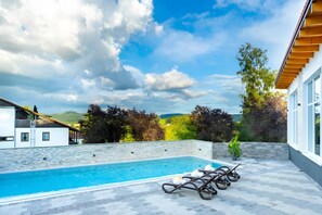 Piscina com espreguiçadeiras e vista para a paisagem ao redor.