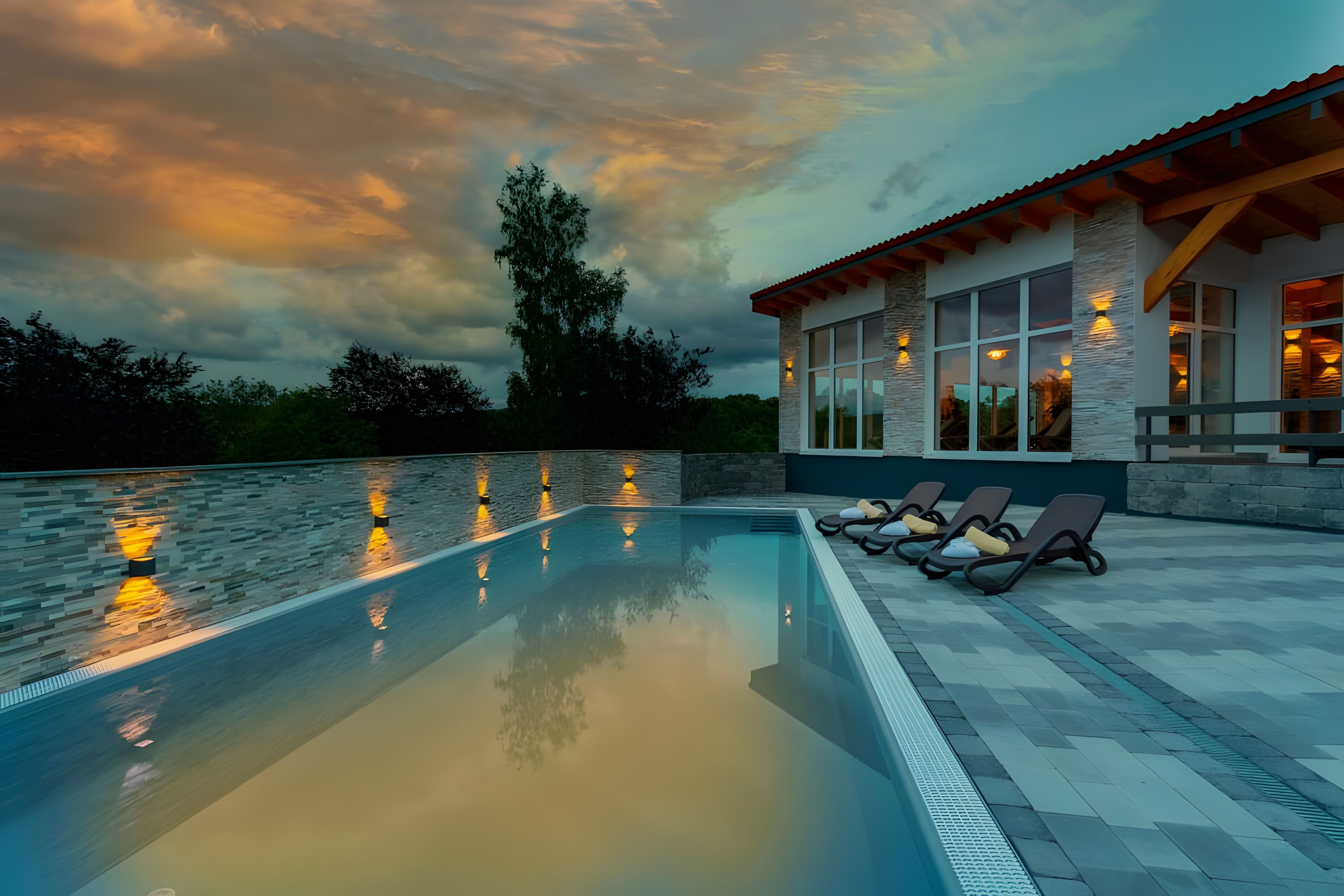 A swimming pool with lounge chairs and a building with large windows.