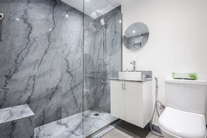 Ein modernes Badezimmer mit einer gläsernen Duschkabine, einem weißen Waschbecken und einer Toilette.