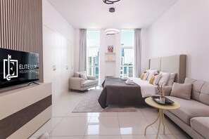 Ein modernes Hotelzimmer mit Bett, Sofa, Fernseher und Blick auf die Stadt.
