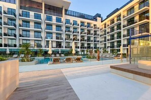 A modern hotel with multiple balconies, a swimming pool, and outdoor seating areas. - Stylish JVC Studio at Binghatti Aurora, Dubai (Dubai)