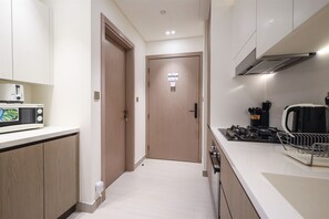 A modern kitchen with white cabinets, a microwave, a stove, and a coffee maker. - Stylish JVC Studio at Binghatti Aurora, Dubai (Dubai)