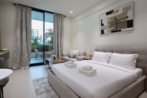 A modern hotel room with a large bed, a sofa, a dining area, and a balcony with a city view. - Stylish JVC Studio at Binghatti Aurora, Dubai (Dubai)